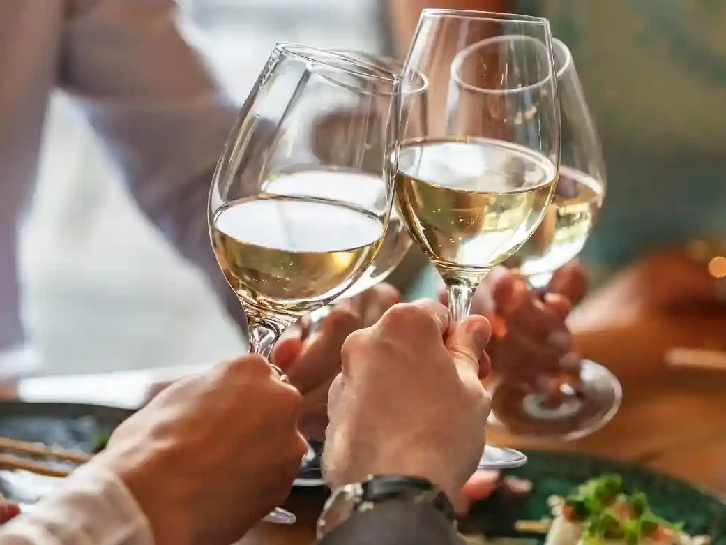 Menschen stoßen mit Weißwein an